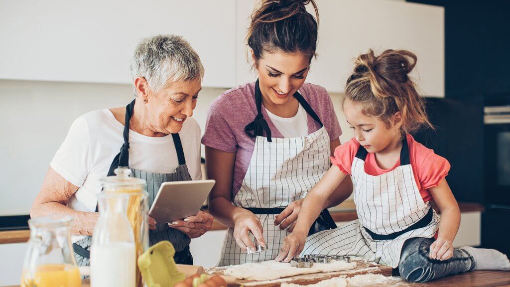 Criança ajudando mãe e avó a cozinhar