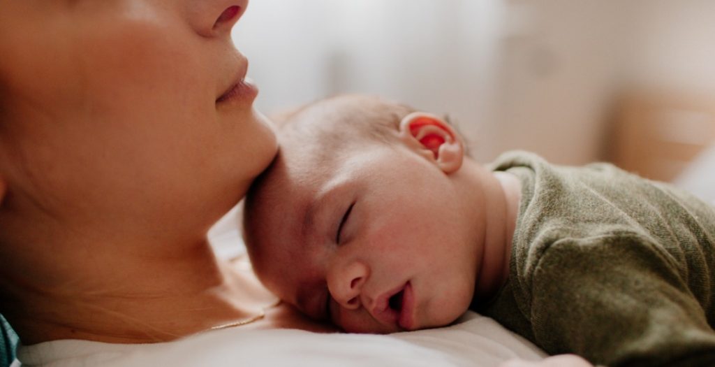 Mãe com bebê deitado sobre o peito