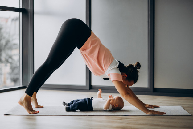 Mãe fazendo pilates com bebê ao lado