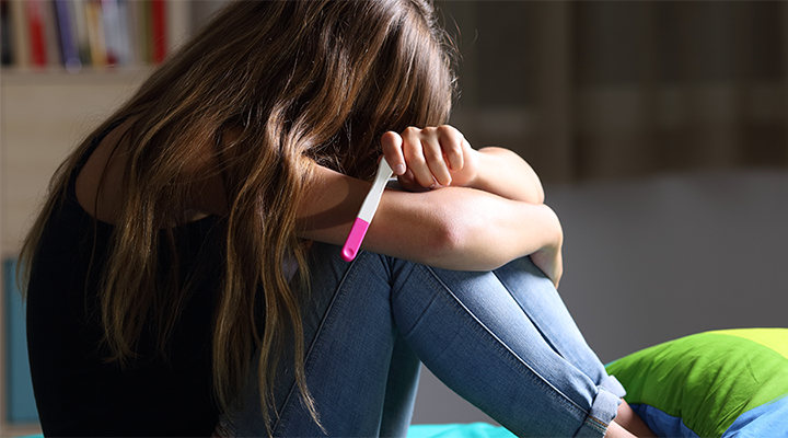 Adolescente com teste de gravidez positivo nas mãos
