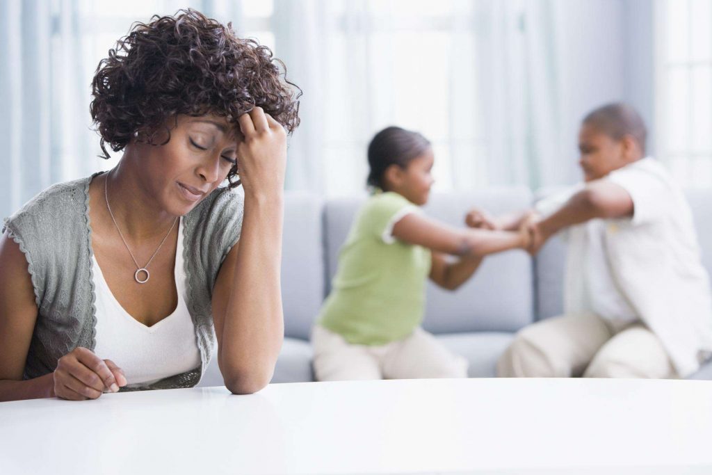Mãe cansada e filhos brigando atrás