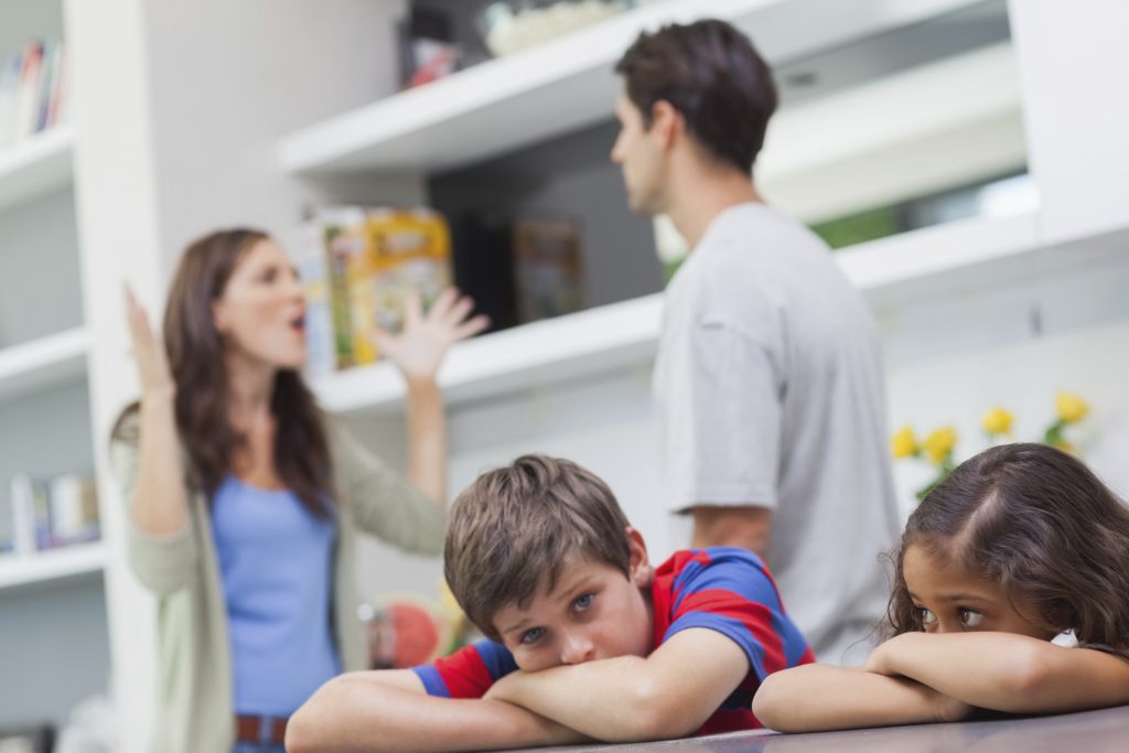 Pais brigando enquanto filhos ouvem e estão tristes