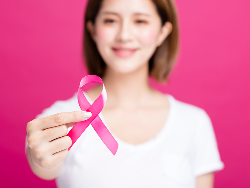 Mulher segurando símbolo do outubro rosa
