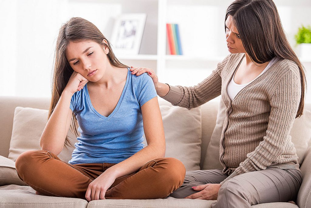 Adolescente recebendo ajuda da mãe